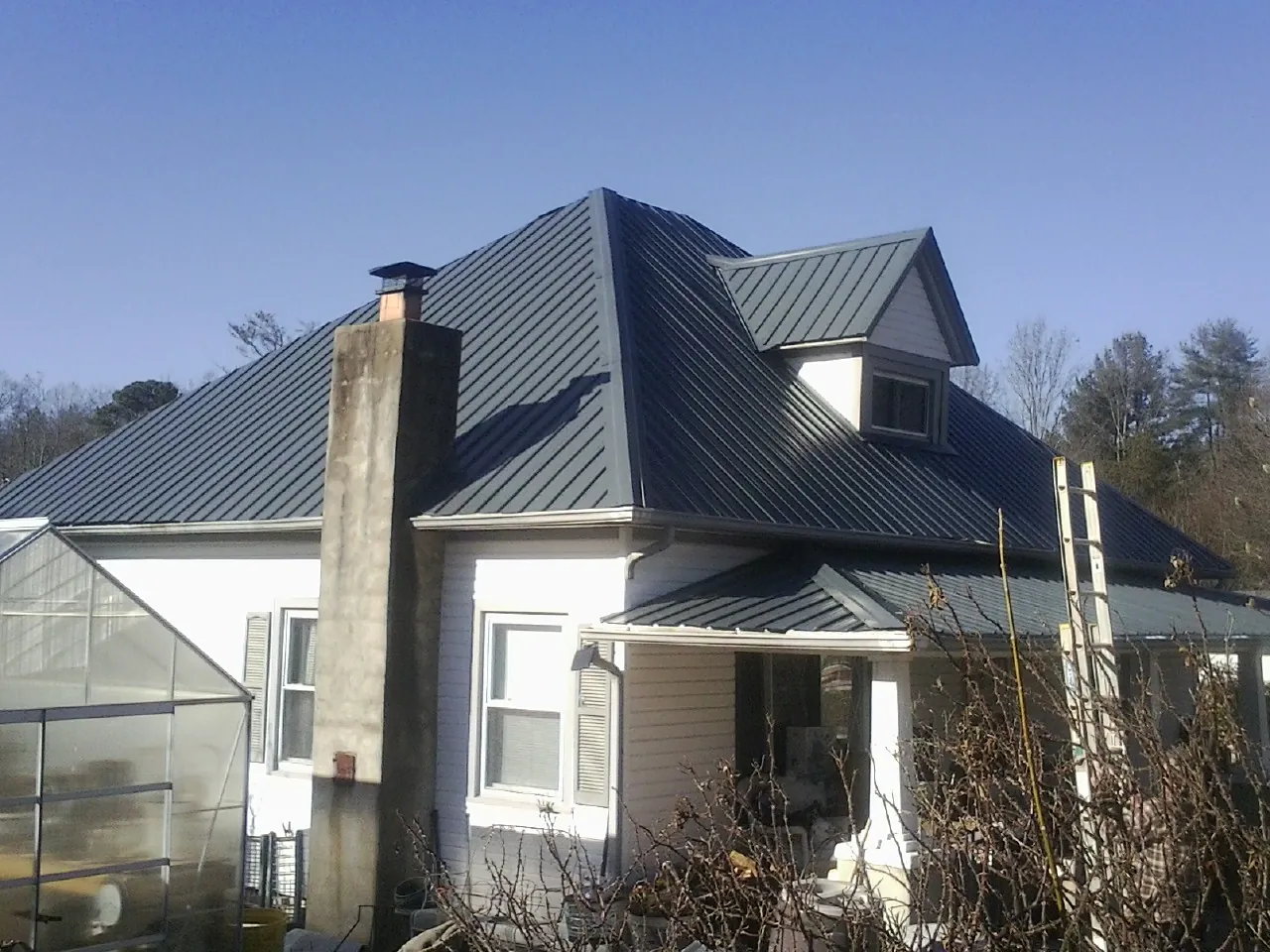 Dark blue standing seam metal roof on a white farmhouse with dormer — Slate & Tile Roof Repair by Roofing Brothers in Sound Beach