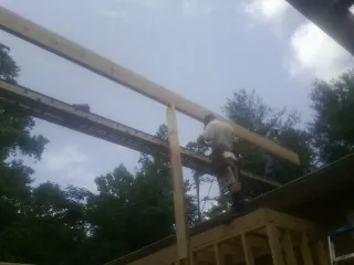 Carpenter setting a ridge beam over a new addition frame — Ice Dam Removal by Roofing Brothers in Sound Beach