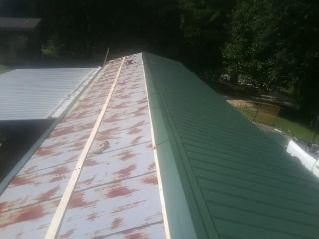 Old rusted panels beside newly installed green metal roofing — Wind Damage Roof Repair by Roofing Brothers in Sound Beach