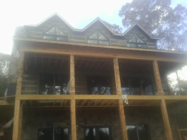 Dormers and porch framing on a large log home under construction — Roof Coating work by our crew in Sound Beach