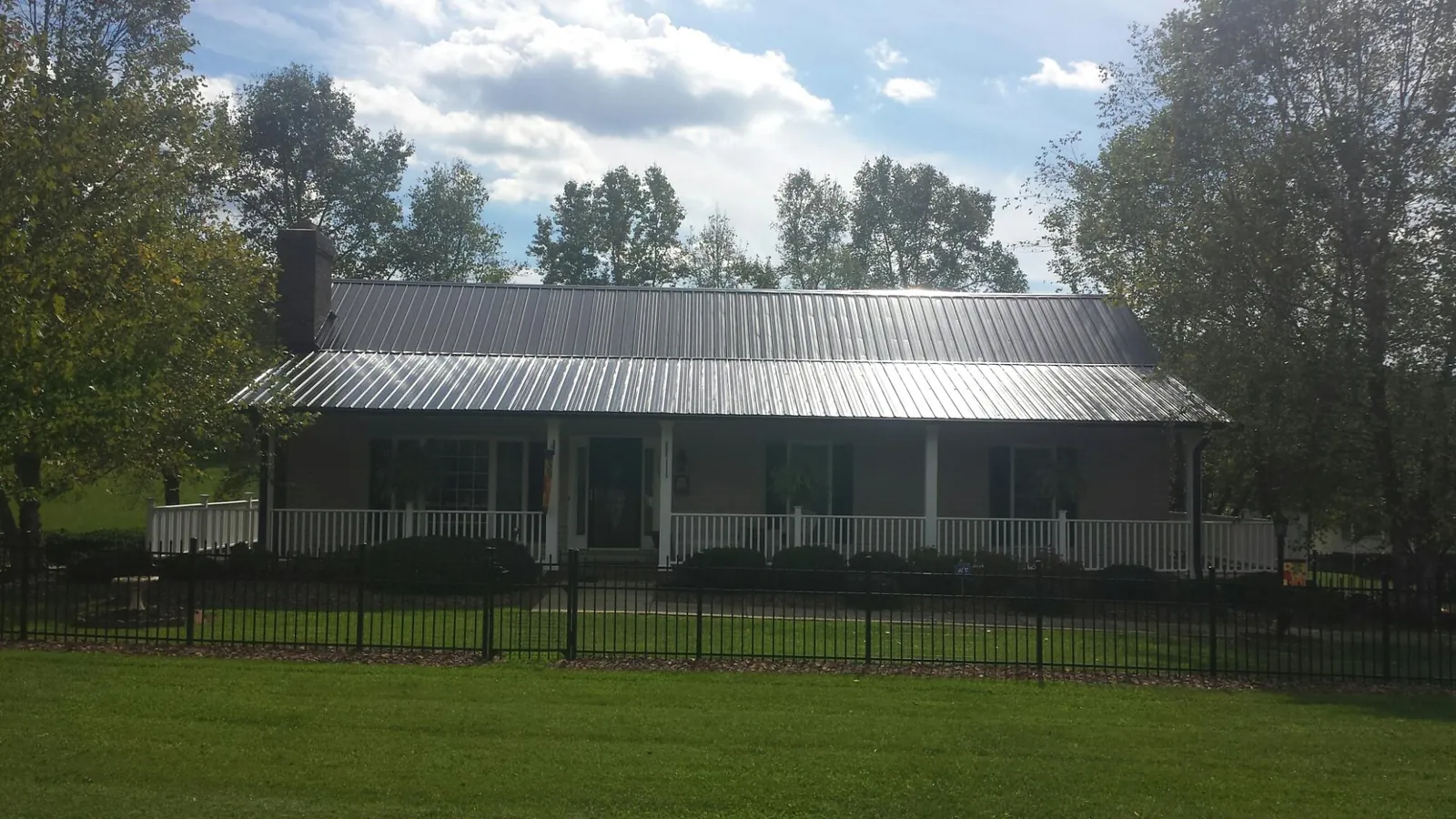 Gray metal roof on a brick ranch with a full width front porch — Gutter Guard Installation work by our crew in Sound Beach