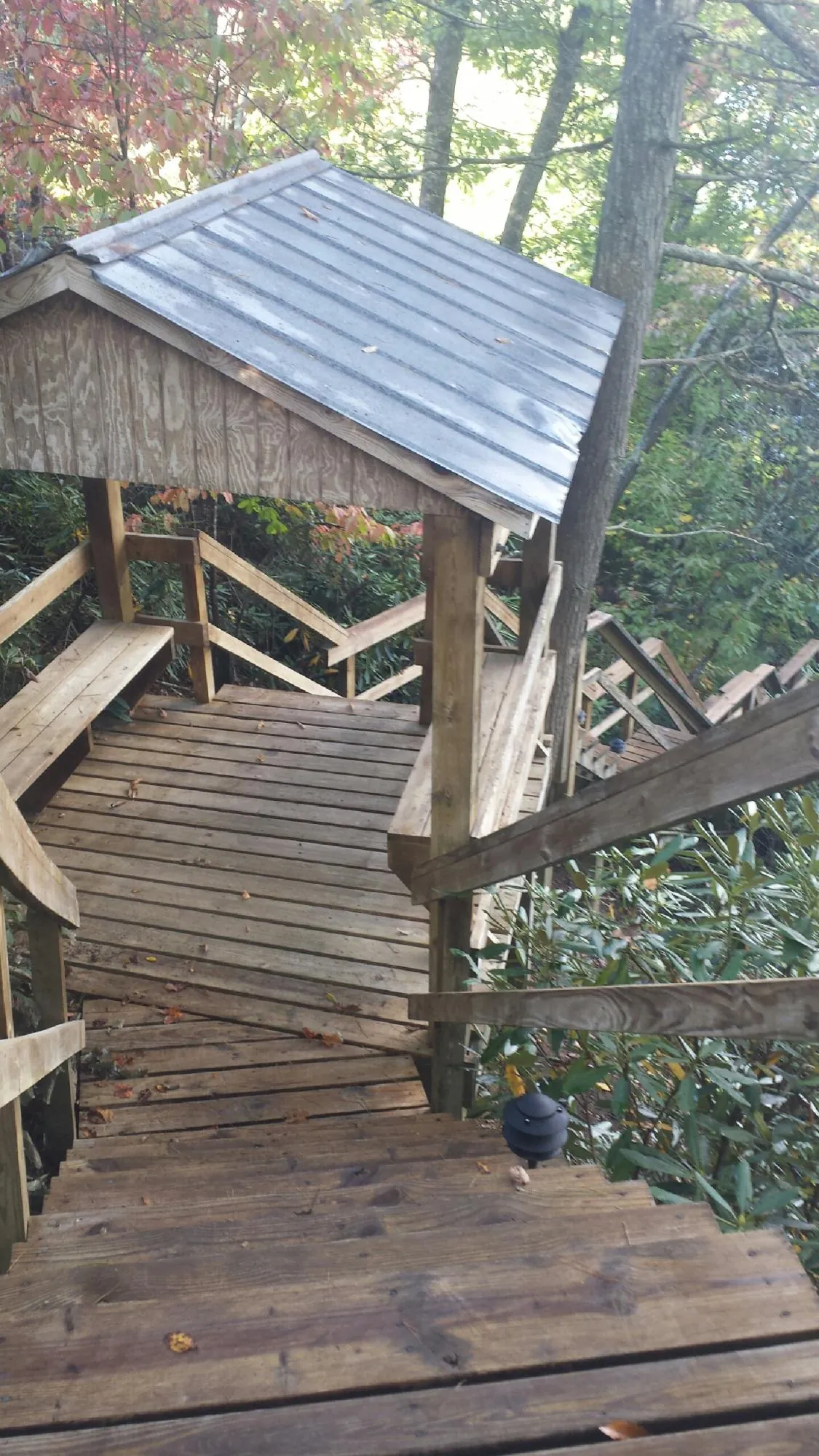 Metal roofed shelter over wooden steps on a wooded walkway — Skylight Repair & Installation work by our crew in Sound Beach