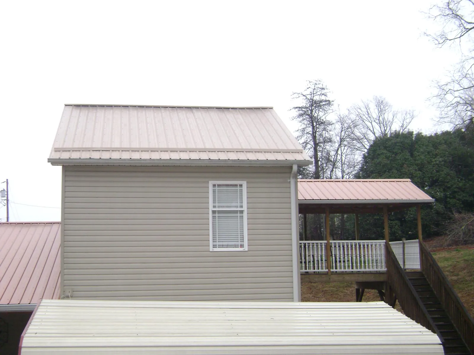 Tan metal roofs on a two story addition and attached porch, from a Roof Replacement job in Sound Beach