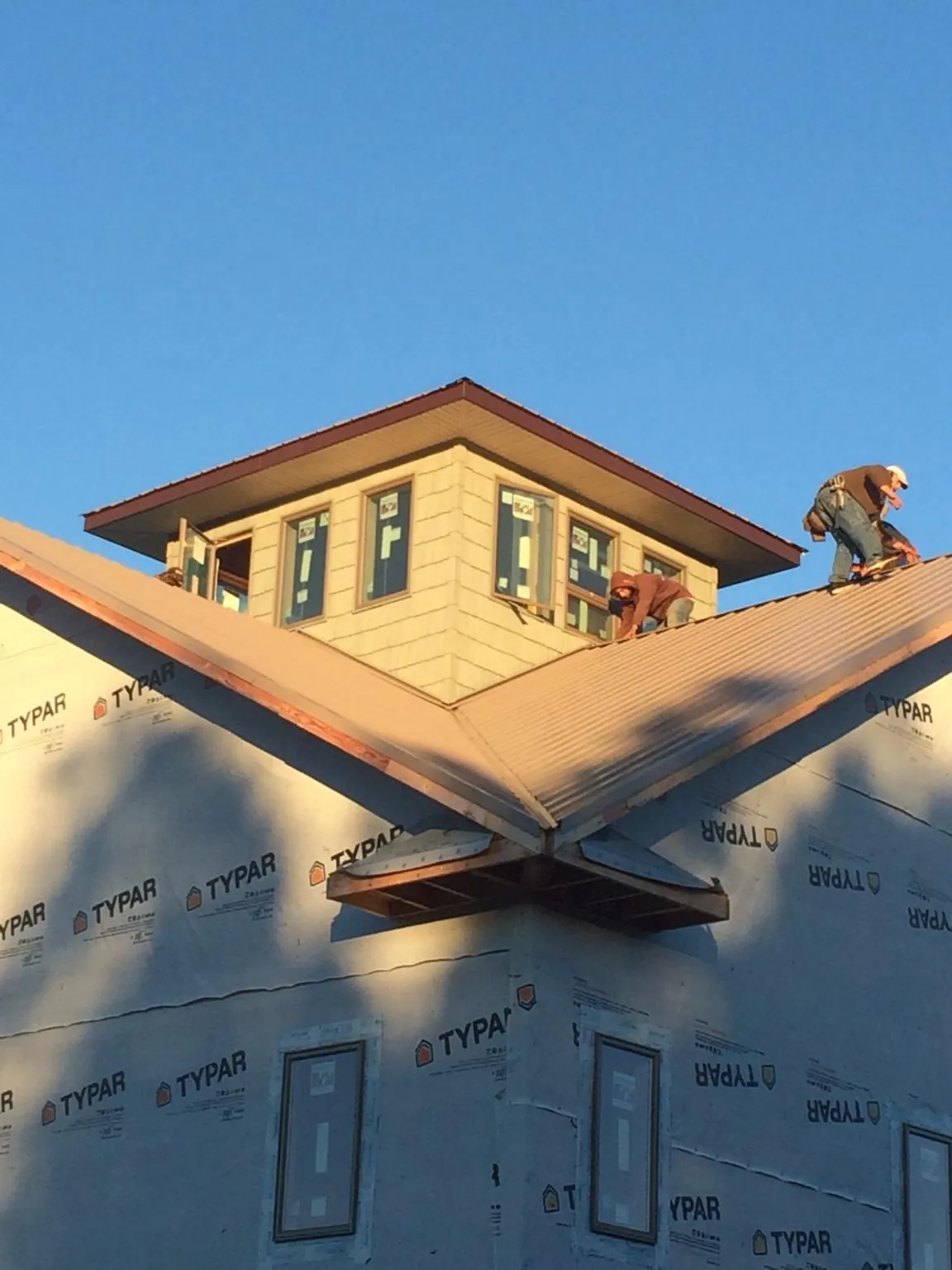 Roofers working around a rooftop cupola on a new metal roof at sunset — Roof Waterproofing in Sound Beach by Roofing Brothers